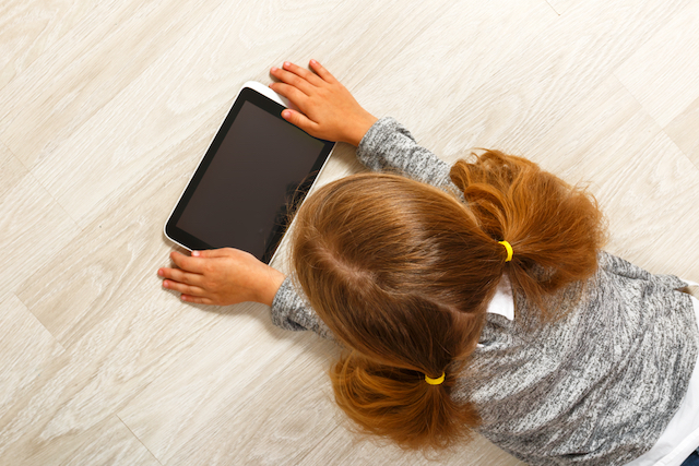 タブレットを使用する女の子の後ろ姿の写真